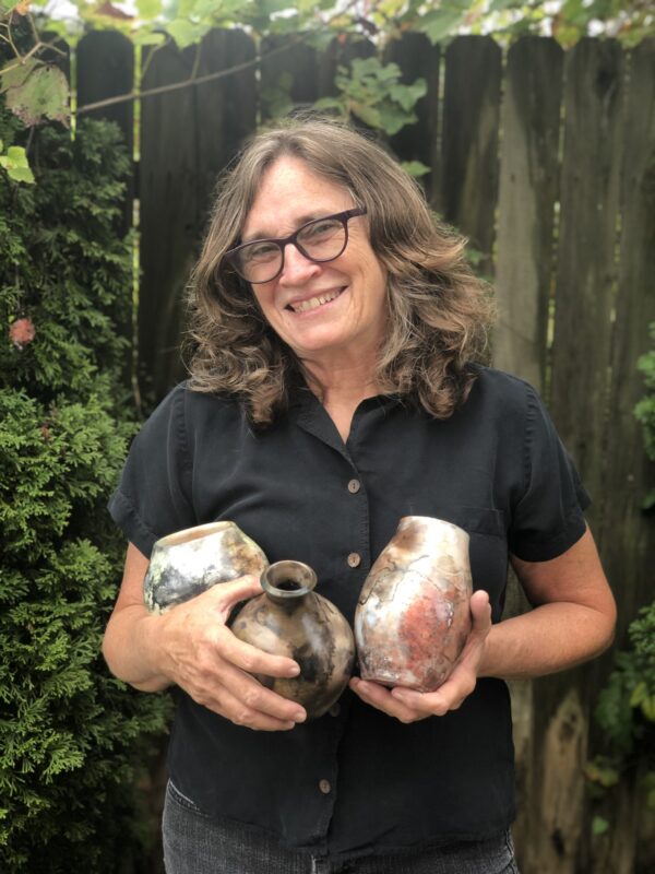 Judi Harwood holding small sagger pots, smiling