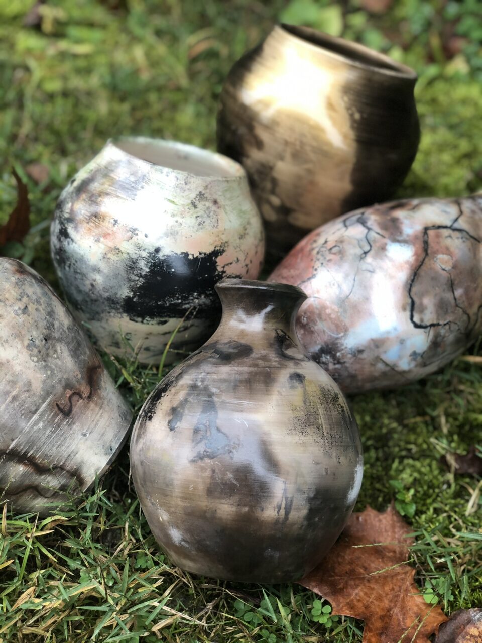 Judi Harwood grouping of finished pots, small sagger pots in the grass Judi Harwood grouping of finished pots, small sagger pots in the grass