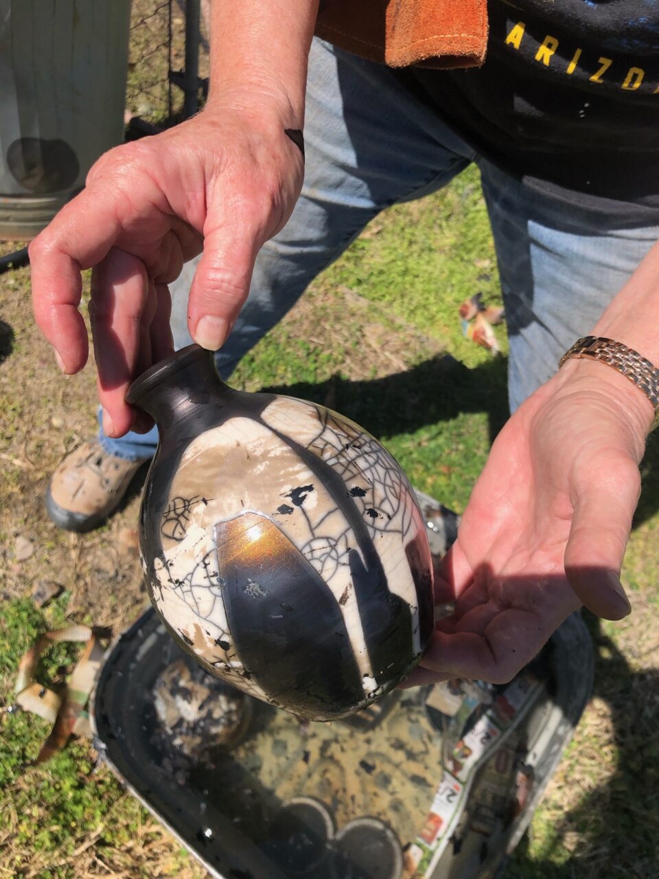 Judi Harwood holding finished raku pot pulled out of water, crackle glaze Judi Harwood holding finished raku pot pulled out of water, crackle glaze