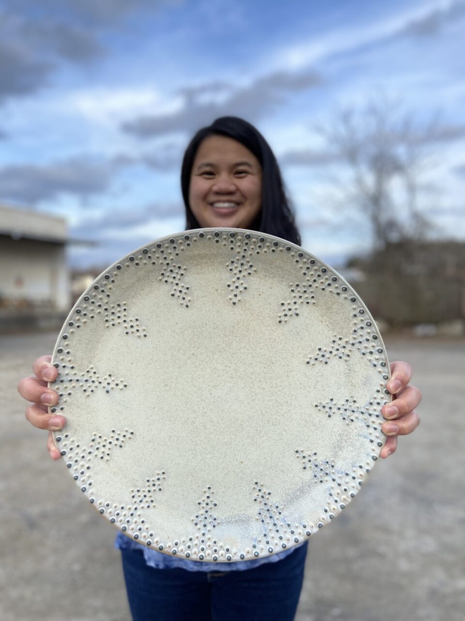 Katie Meili Messersmith holding finished pot, dotted serving platter, infinite cobalt whisper pattern Katie Meili Messersmith holding finished pot, dotted serving platter, infinite cobalt whisper pattern