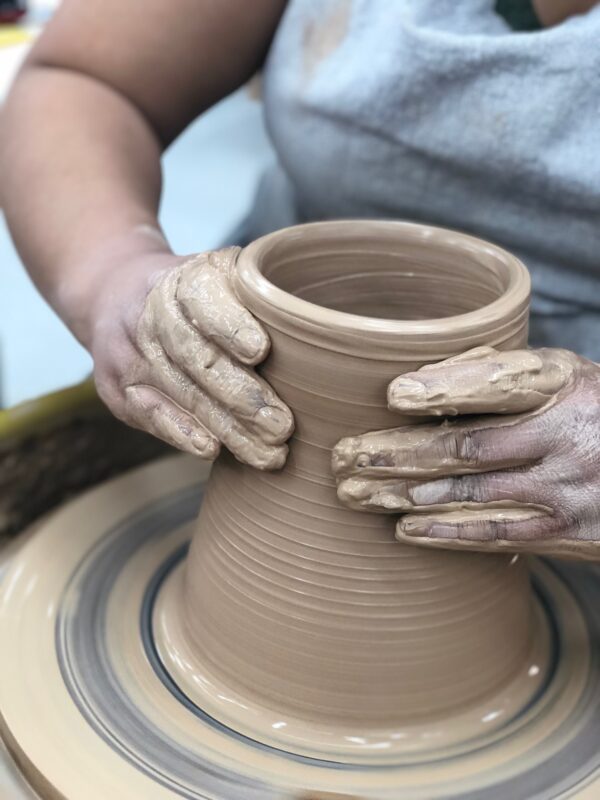 Close up of Katie Meili Messersmith hands throwing on potters wheel, red clay, collaring 2, our stock image