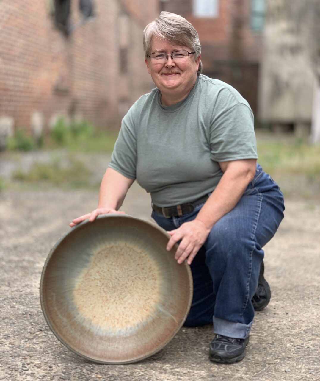Julia Mann kneeling with her finished pot, large bowl, smiling Julia Mann kneeling with her finished pot, large bowl, smiling