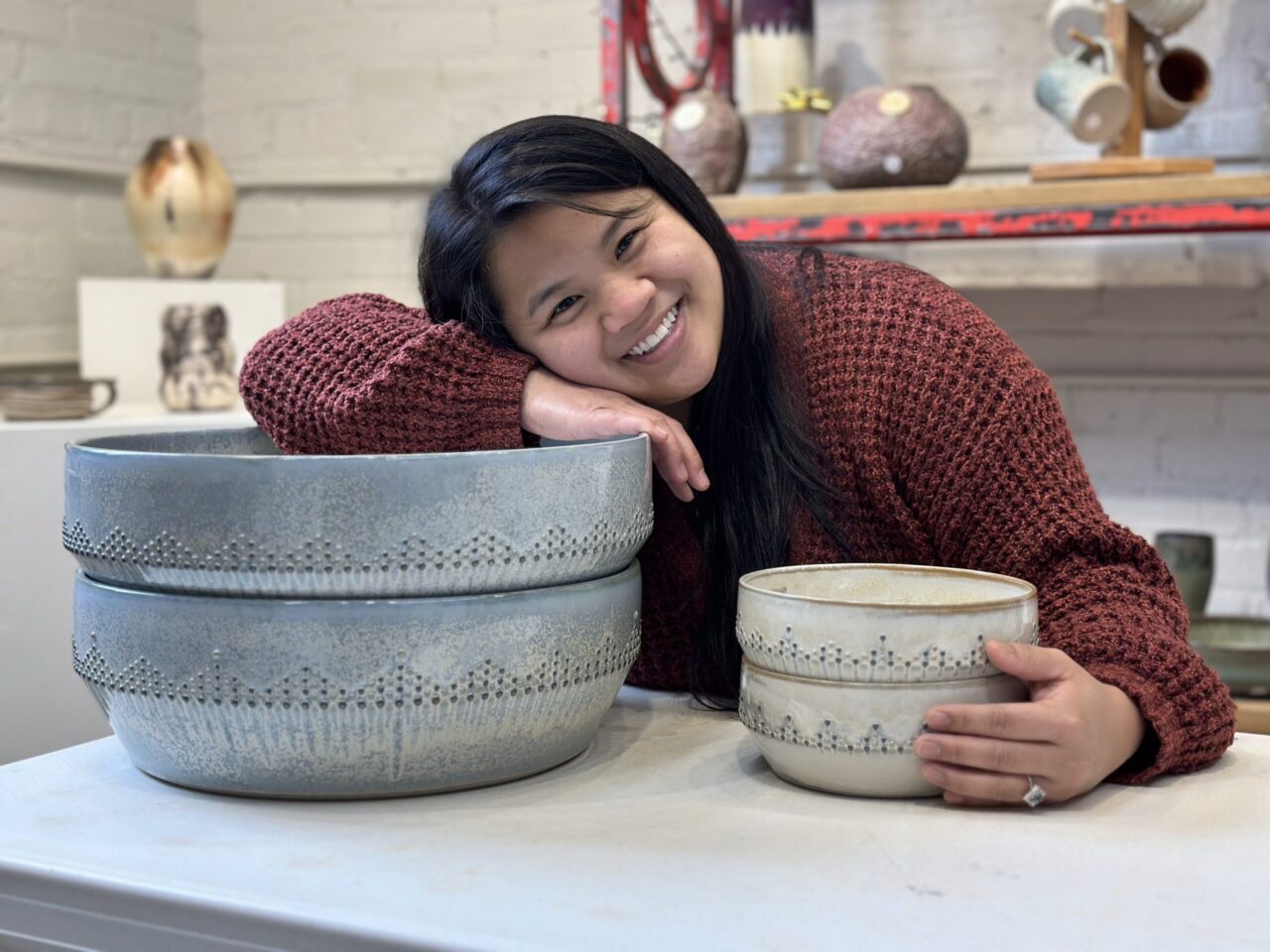Katie Meili Messermith with finished pots, dot pots, large pasta bowls, dotted pasta bowl, smiling Katie Meili Messermith with finished pots, dot pots, large pasta bowls, dotted pasta bowl, smiling