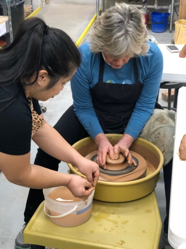 Katie Meili Messersmith teaching TC student, throwing on potters wheel