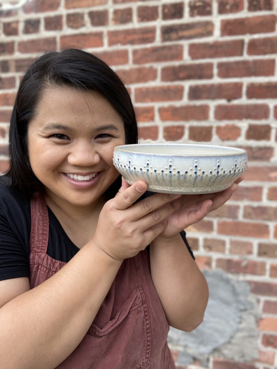 Katie Meili Messersmith holding finished pot close to face, dotted pasta bowl, dot pots Katie Meili Messersmith holding finished pot close to face, dotted pasta bowl, dot pots