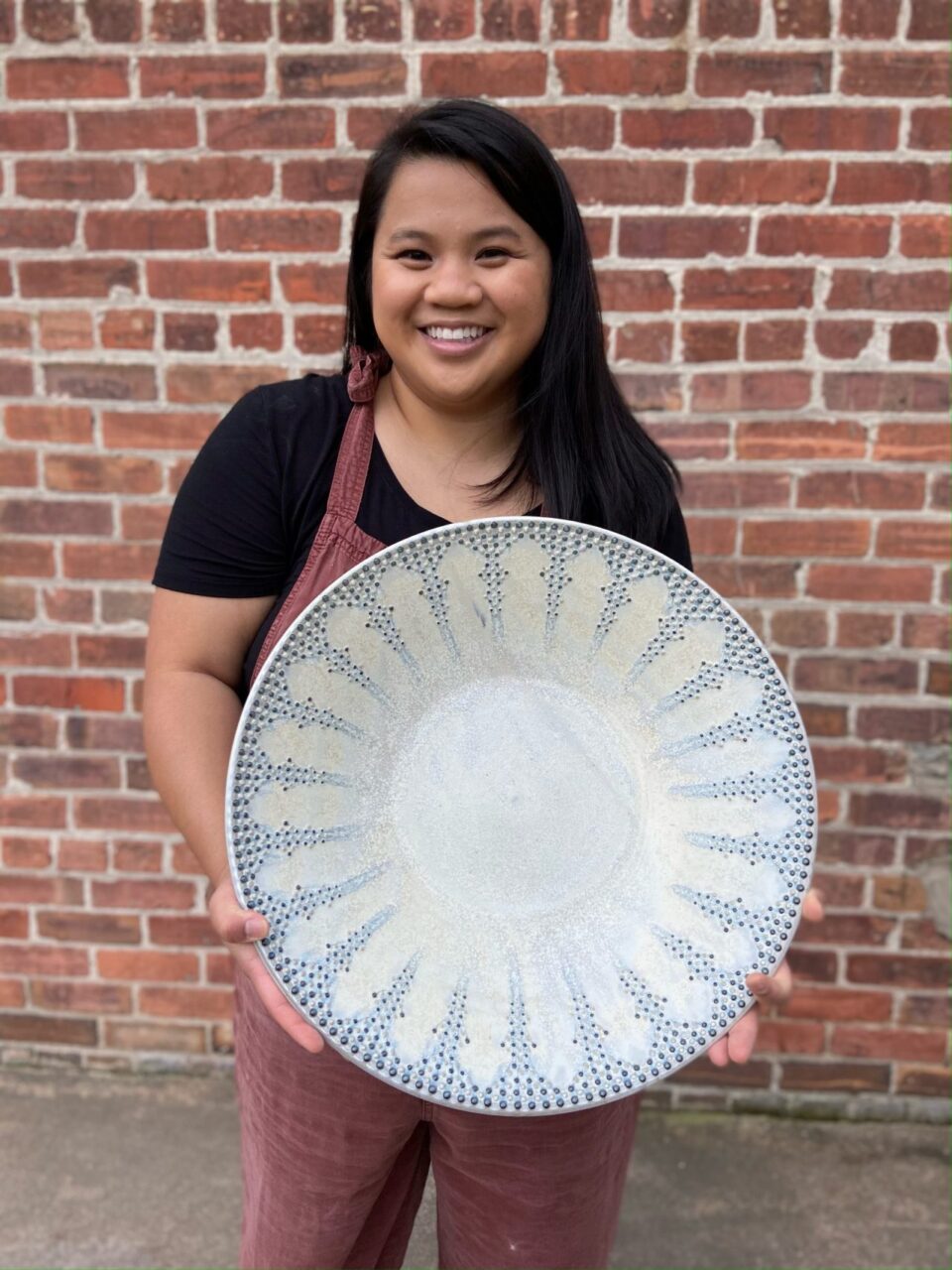 Katie Meili Messersmith holding large statement bowl, dot pots, finished pot, infinite cobalt whispers, smiling Katie Meili Messersmith holding large statement bowl, dot pots, finished pot, infinite cobalt whispers, smiling