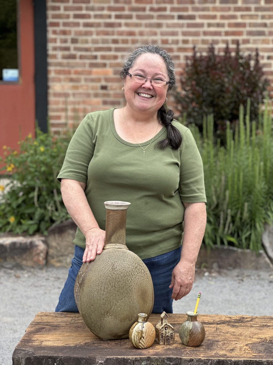 Karen Dubois standing with grouping of her finished pots, wood soda kazie pots, large vase Karen Dubois standing with grouping of her finished pots, wood soda kazie pots, large vase