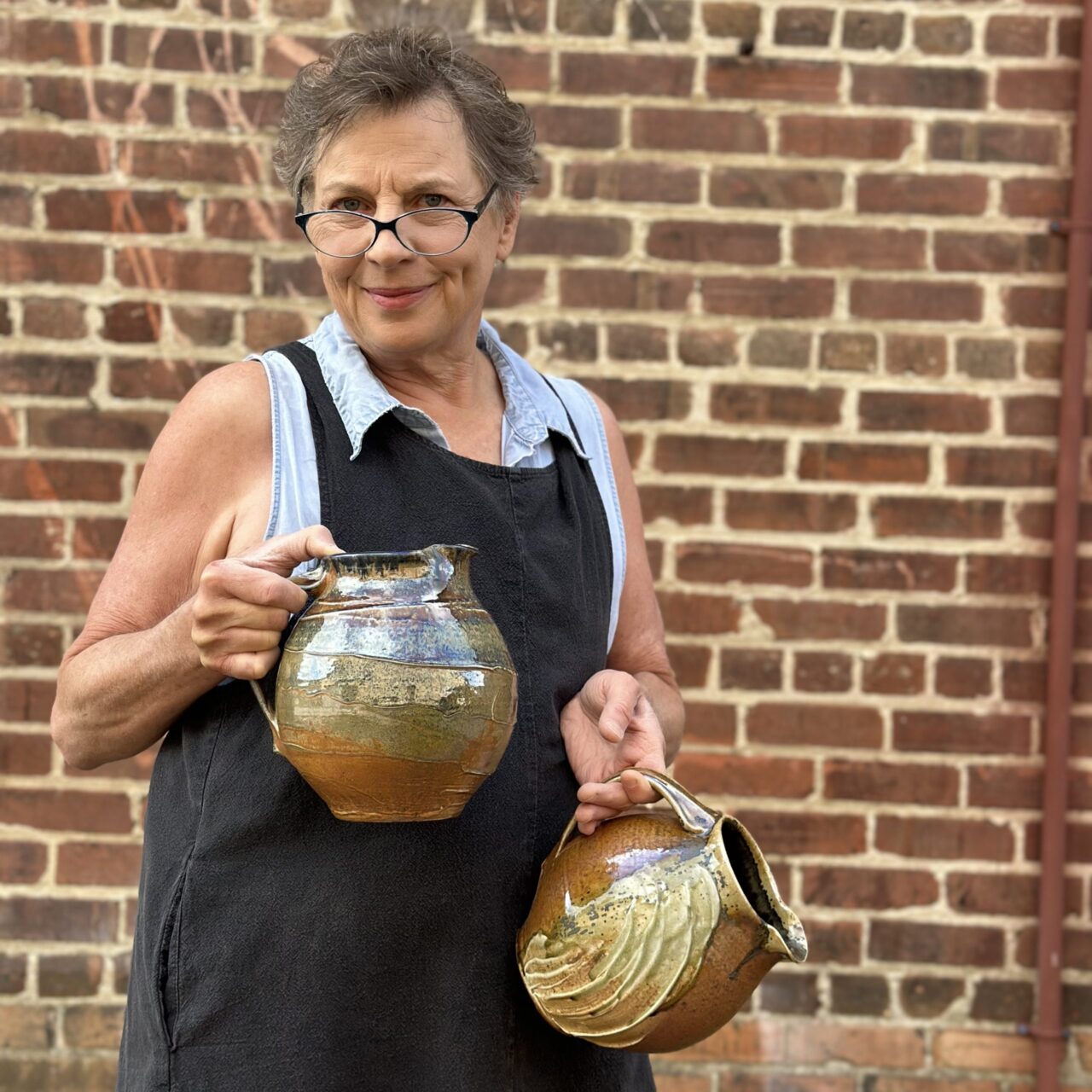 Sarah Wells Rolland holding two finished pots, wood soda kazie pitchers Sarah Wells Rolland holding two finished pots, wood soda kazie pitchers