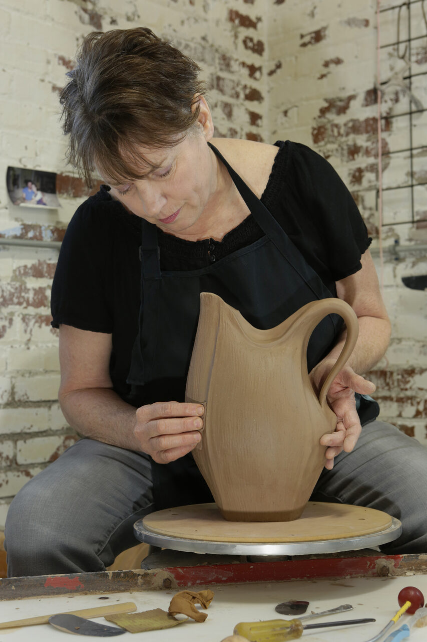 Sarah Wells Rolland sculpting shaping her signature closed form pitcher on potters wheel Sarah Wells Rolland sculpting shaping her signature closed form pitcher on potters wheel