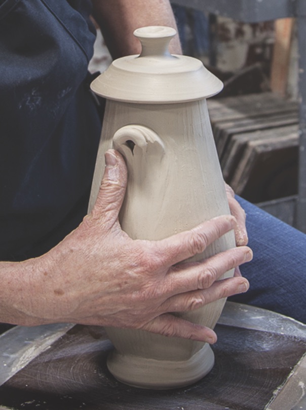 Close up of Sarah Wells Rolland hands sculpting an added handle to a lidded jar Close up of Sarah Wells Rolland hands sculpting an added handle to a lidded jar