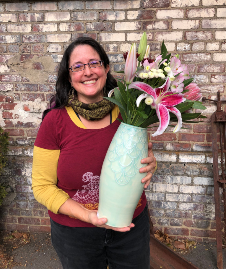 Maria Andrade Troya holding finished pot, vase with flowers Maria Andrade Troya holding finished pot, vase with flowers